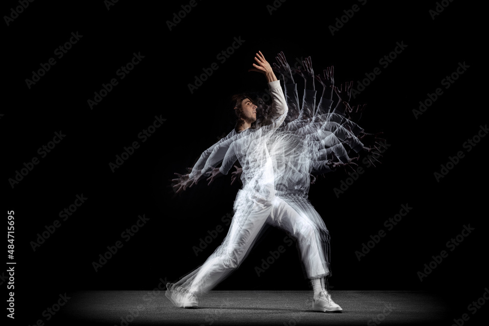 Young man, hip-hop dancer in action, motion isolated on dark background with sroboscope effect. Youth culture, hip-hop, movement, style and fashion, action.