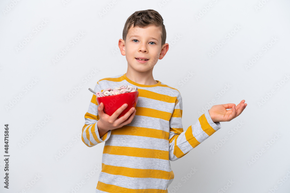 Little caucasian boy holding a cereal bowl isolated on white background extending hands to the side for inviting to come Little caucasian boy holding a cereal bowl isolated on white background extending hands to the side for inviting to come