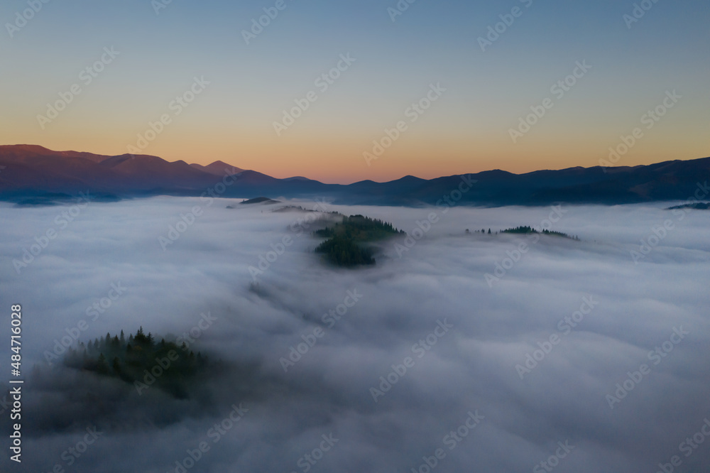 Beautiful landscape with thick mist in mountains at sunset. Drone photography