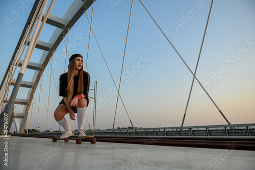 Young woman riding her longboard on the bridge