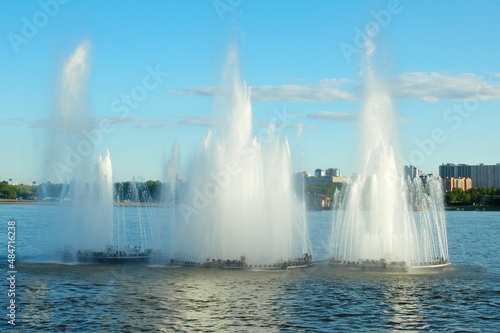 Three fountains on the water of river. Sunny day.