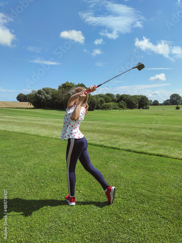 Cute teen girl playing golf on grass at golf club in summer
