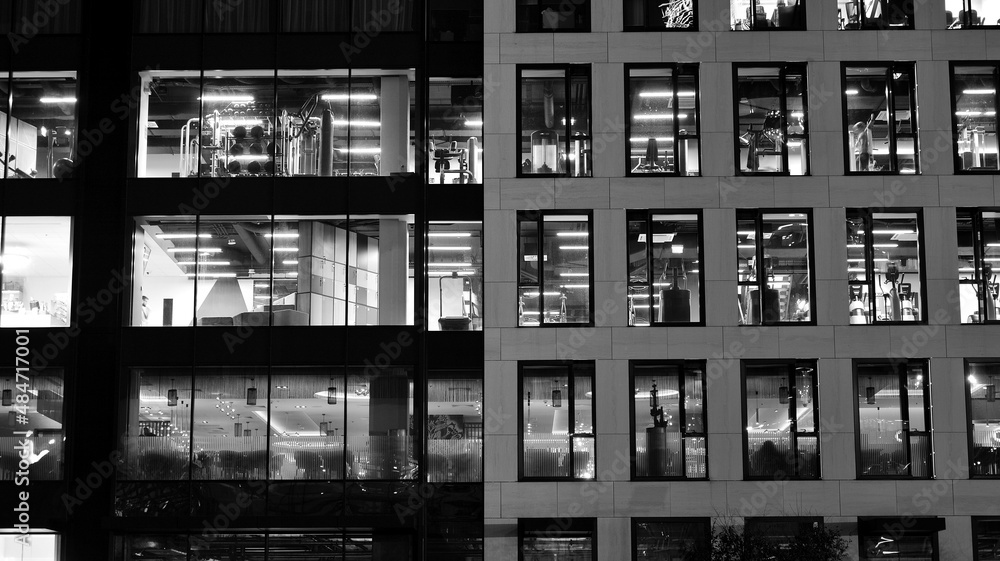 Amazing night cityscape. Office building at night, building facade with glass and lights. View with illuminated modern skyscraper. Scenic glowing windows of skyscrapers at evening. Black and white. Amazing night cityscape. Office building at night, building facade with glass and lights. View with illuminated modern skyscraper. Scenic glowing windows of skyscrapers at evening. Black and white.