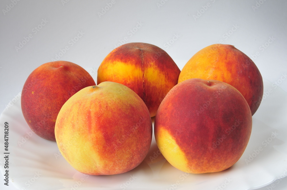 Bright, juicy peaches on a white dish Bright, juicy peaches on a white dish