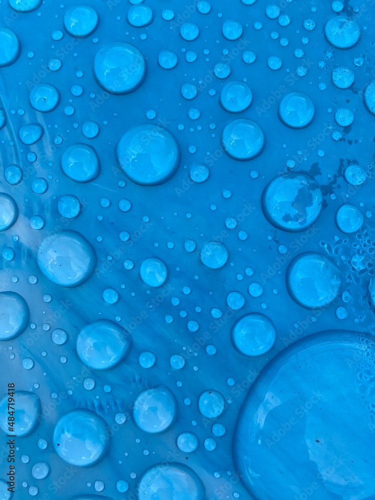 rain water drops on blue cyan turquoise plastic background with copy space 