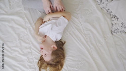 view top. a little girl laughs with tickling on the bed. games of children photo