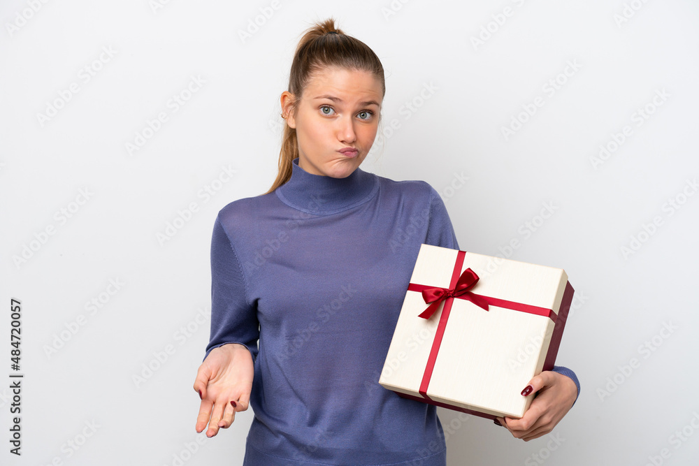 Young caucasian woman holding a gift isolated on white background making doubts gesture while lifting the shoulders Young caucasian woman holding a gift isolated on white background making doubts gesture while lifting the shoulders