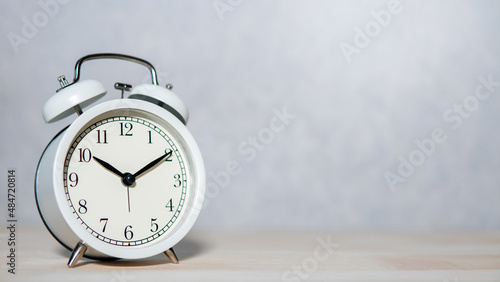 White retro analog alarm clock on wooden table. Time management concept