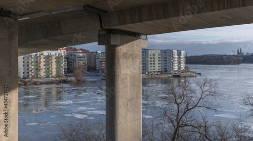 Foundation of a bridges parts of the high way Essingeleden and apartment houses at the waterfront of the district island Lilla Essingen, ice floats and reflections a cold sunny winter day in Stockholm photo