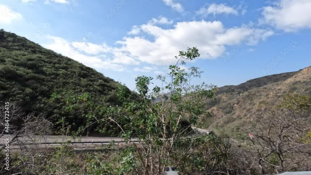 Side driving view of road work ahead sign on curving Potrero Canyon Road in rural Ventura County California. Side driving view of road work ahead sign on curving Potrero Canyon Road in rural Ventura County California.