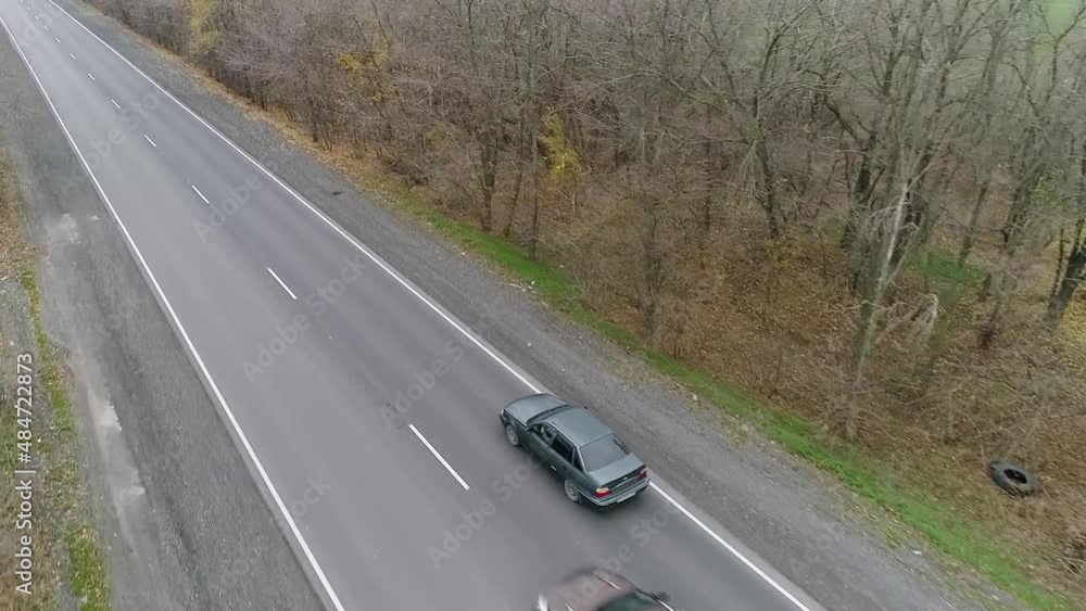 Car overtakes another car on highway outside the city on cloudy day, shot from drone Car overtakes another car on highway outside the city on cloudy day, shot from drone