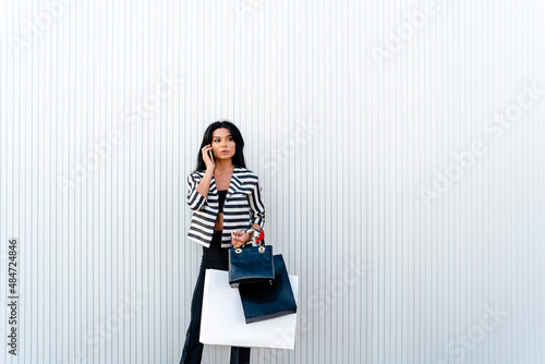 Elegant woman talking on smartphone near modern architecture wall photo