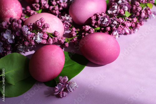 Close-up of beautiful lilac Easter eggs with blooming lilac branches. Easter decor. Selective focus.