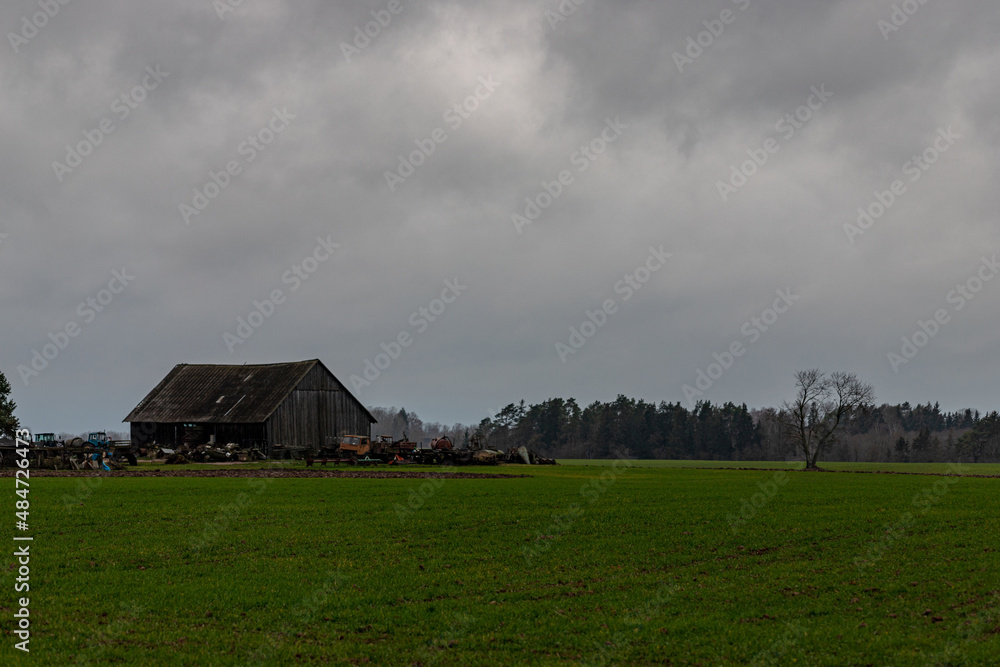 There is grassland and old abandoned broken tractors by the old wooden farm house There is grassland and old abandoned broken tractors by the old wooden farm house