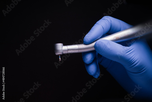 Fotografie, Obraz a dental tip and a metal bur in dentistry treats caries a blue gloved hand holds