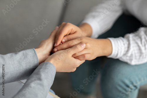 Psychological support. Psychotherapist offering help to young woman, holding her hands during psychotherapy session