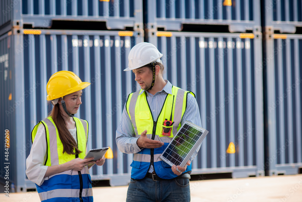 Man and women caucasian team engineer standing and wearing safety work equipment clothes are discussing how to install solar panels. to be used as electric power for lighting at night of warehouse. Man and women caucasian team engineer standing and wearing safety work equipment clothes are discussing how to install solar panels. to be used as electric power for lighting at night of warehouse.