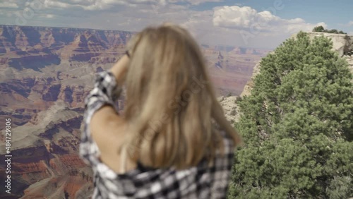 A young woman looking to Horseshoe Bend and Colorado river from the edge of 1000ft canyon in Glen Canyon National Recreation Area, Arizona, USA photo