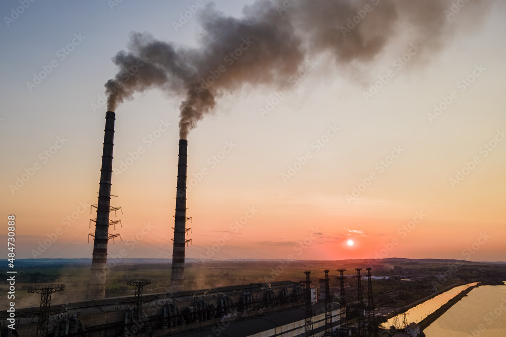 Aerial view of coal power plant high pipes with black smoke moving upwards polluting atmosphere at sunset. Production of electrical energy with fossil fuel concept