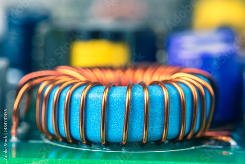 Macro view of electronic component, induction coil with copper wire winding on magnetic ferrite core on circuit board
