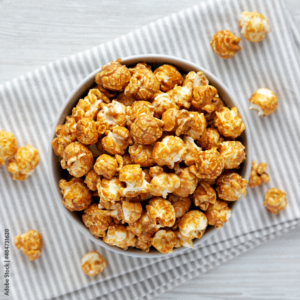 Homemade Caramel Popcorn in a gray Bowl on a white wooden background, top view. Flat lay, overhead, from above. Homemade Caramel Popcorn in a gray Bowl on a white wooden background, top view. Flat lay, overhead, from above.