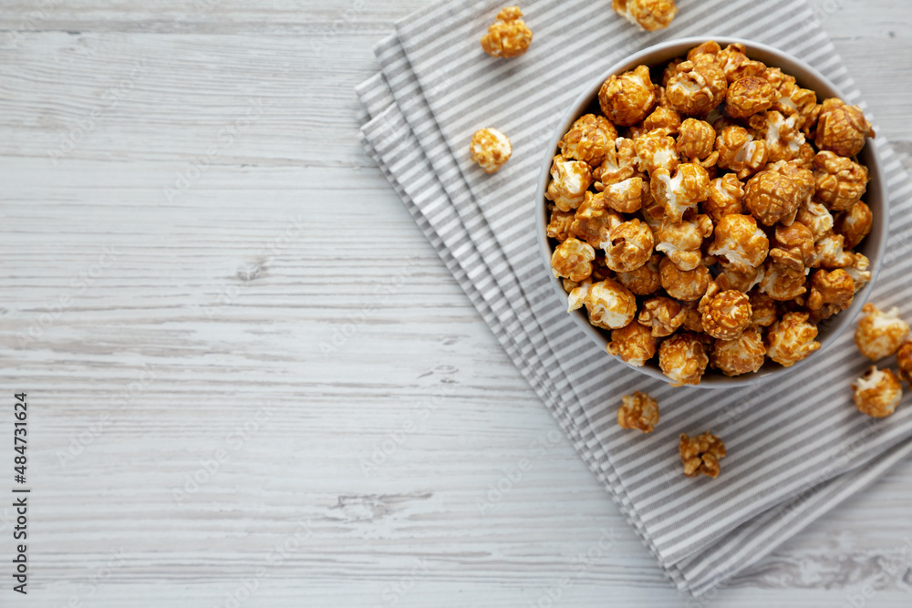 Homemade Caramel Popcorn in a gray Bowl on a white wooden background, top view. Flat lay, overhead, from above. Space for text.