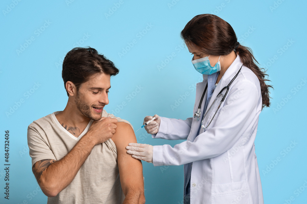 Vaccination Concept. Female Doctor With Syringe Making Vaccine Injection To Male Patient Vaccination Concept. Female Doctor With Syringe Making Vaccine Injection To Male Patient