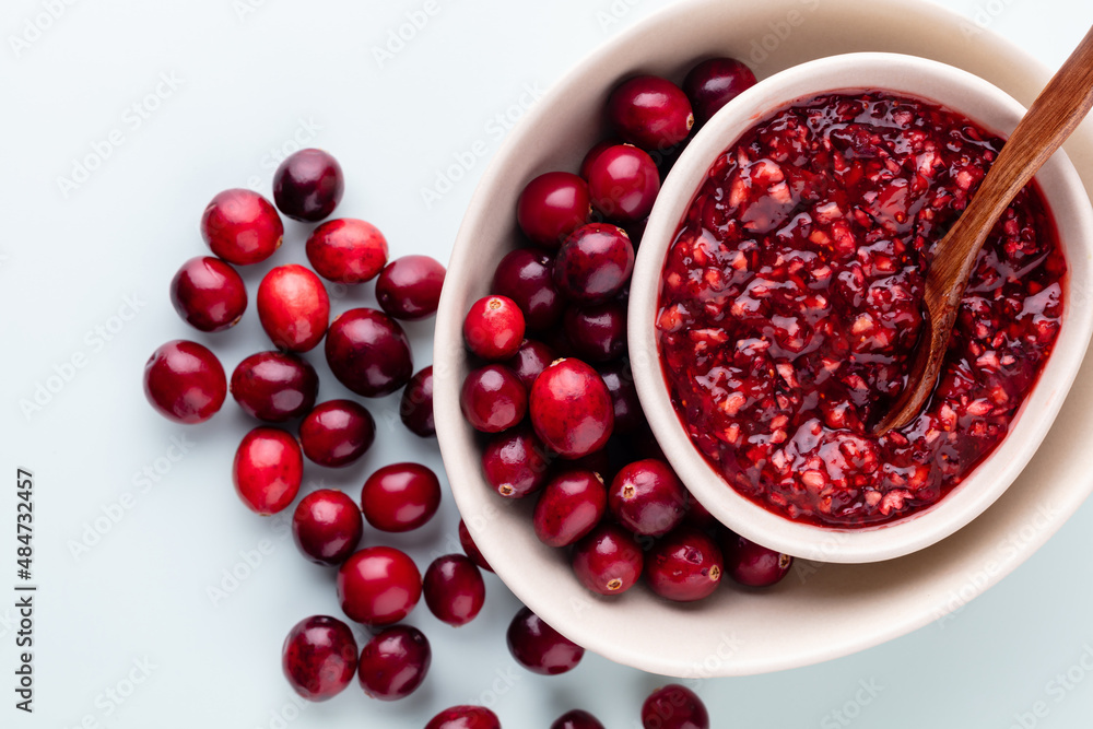 Cranberries in white bowl on pastel background. Cranberries in white bowl on pastel background.