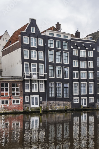 Damrak Waterfront: Typical old Dutch houses at Damrak water canal. Amsterdam, Netherlands.