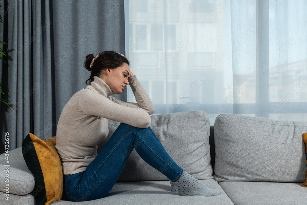 Young sad woman with broken heart sitting alone at home suffering from depression anxiety and bad mental condition. Female having hard time and burnout of overthinking and worry Young sad woman with broken heart sitting alone at home suffering from depression anxiety and bad mental condition. Female having hard time and burnout of overthinking and worry