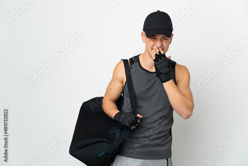Young sport caucasian man with bag isolated on white background happy and smiling covering mouth with hand