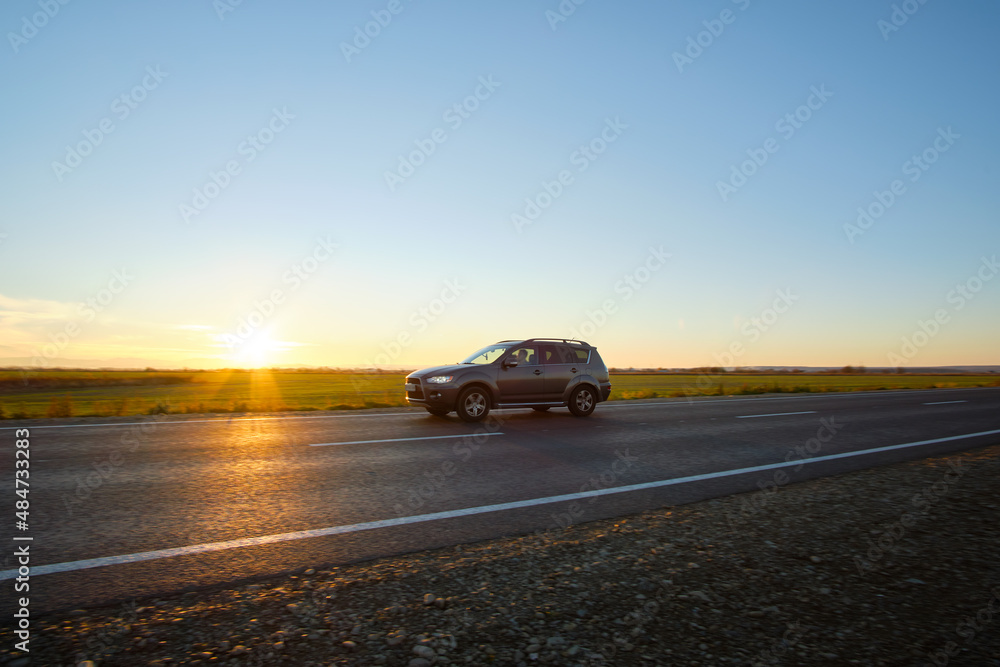 Car driving fast on intercity road at sunset. Highway traffic in evening Car driving fast on intercity road at sunset. Highway traffic in evening