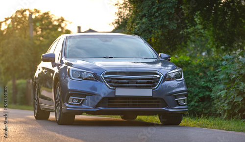 Front view of new shiny expensive car parked on city street side in evening