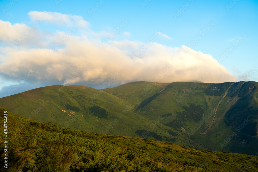 Misty evening over high mountain peaks and distant valley at bright sunset. Amazingl scenery of wild hillside at dusk