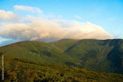 Misty evening over high mountain peaks and distant valley at bright sunset. Amazingl scenery of wild hillside at dusk