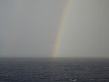 Rainbow over ocean with cloudy sky