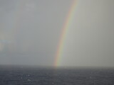 Rainbow over ocean with cloudy sky