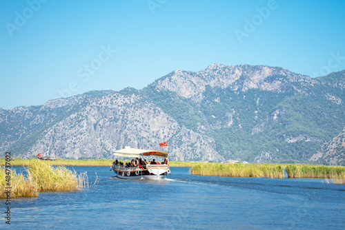 Tourist pleasure boat on the Dalyan River, next to the rocks, which contain the Lycian tombs, in Mugla Province located between the districts of Marmaris and Fethiye on the south-west coast of Turkey photo
