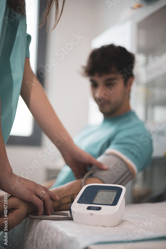 Foto Doctor taking blood pressure and pulse on the arm of a patient in the clinic