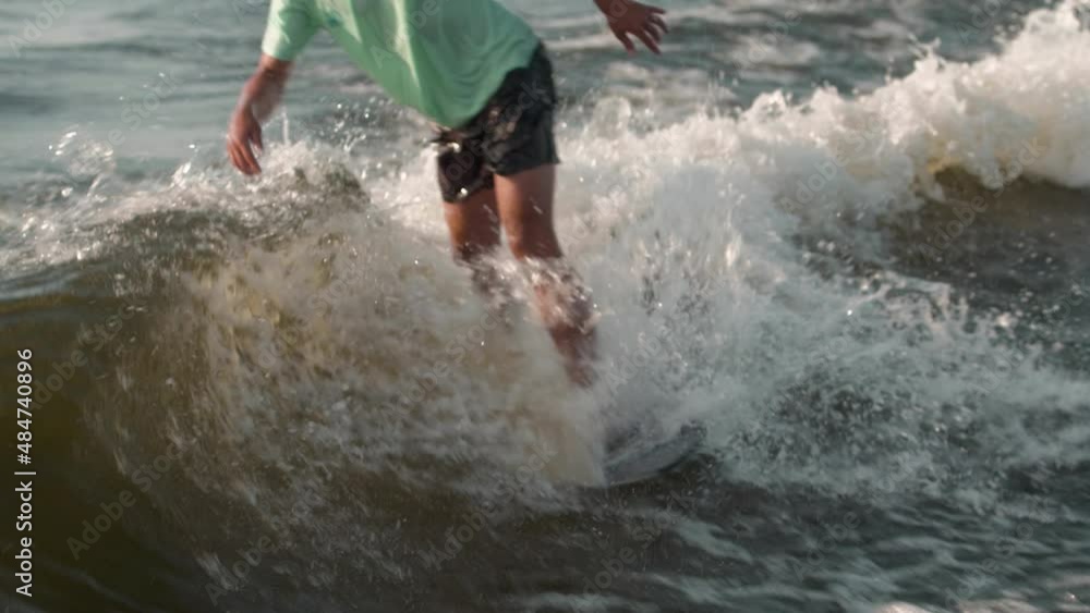 A surfer jumping on a wakeboard. An experienced wakeboarder sprays water drops into the camera. A surfer jumping on a wakeboard. An experienced wakeboarder sprays water drops into the camera.