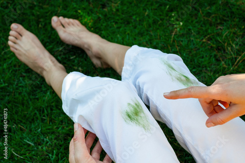 Hand showing dirty stain of grass on white pants from unexpected accident. top view. daily life stain concept. outodoors.  photo