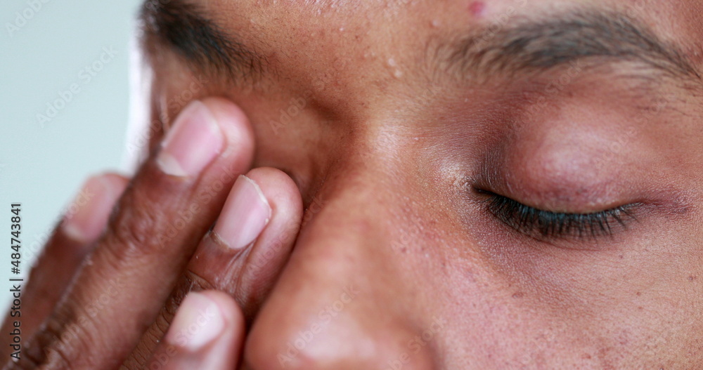Tired man rubbbing eye with hand. Exhausted african american touching face Tired man rubbbing eye with hand. Exhausted african american touching face