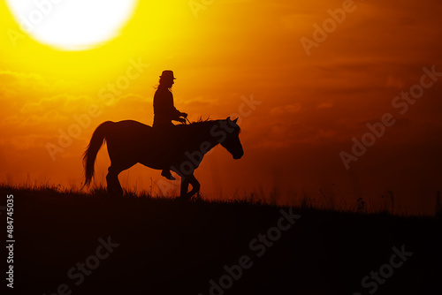 silhouette of a woman riding a horse with the setting sun