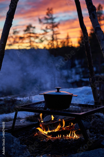 Outdoor cooking on an open fire with sunset in the background