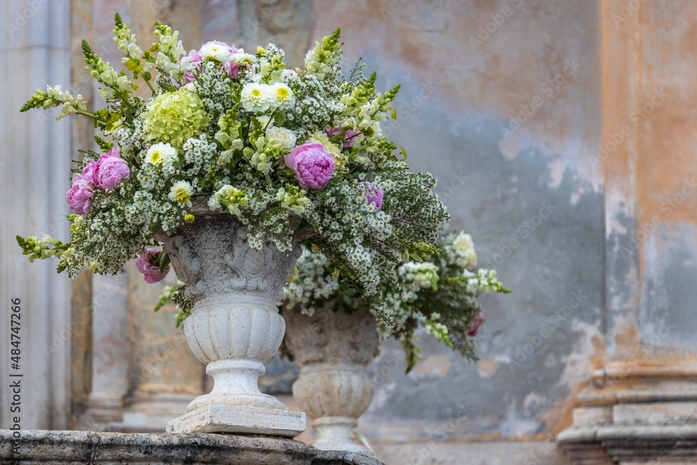 Romantischer Hochzeitsstrauß in einer barocken Steinvase vor der Chiesa di San Giuseppe in Taormina in Italien Romantischer Hochzeitsstrauß in einer barocken Steinvase vor der Chiesa di San Giuseppe in Taormina in Italien
