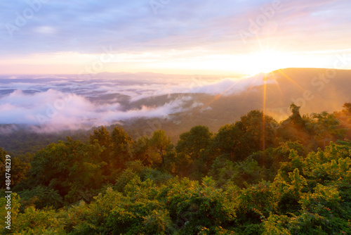 Morning sun rays through clouds and fog over mountains at Arkansas Grand Canyon Scenic Overlook