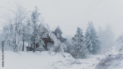 Abandoned mountain chalet in Bozi Dar Czech Republic during icy foggy, winter time in Ore Mountains (Erzgebirge). Mist, snow and fog covering frozen landscape.