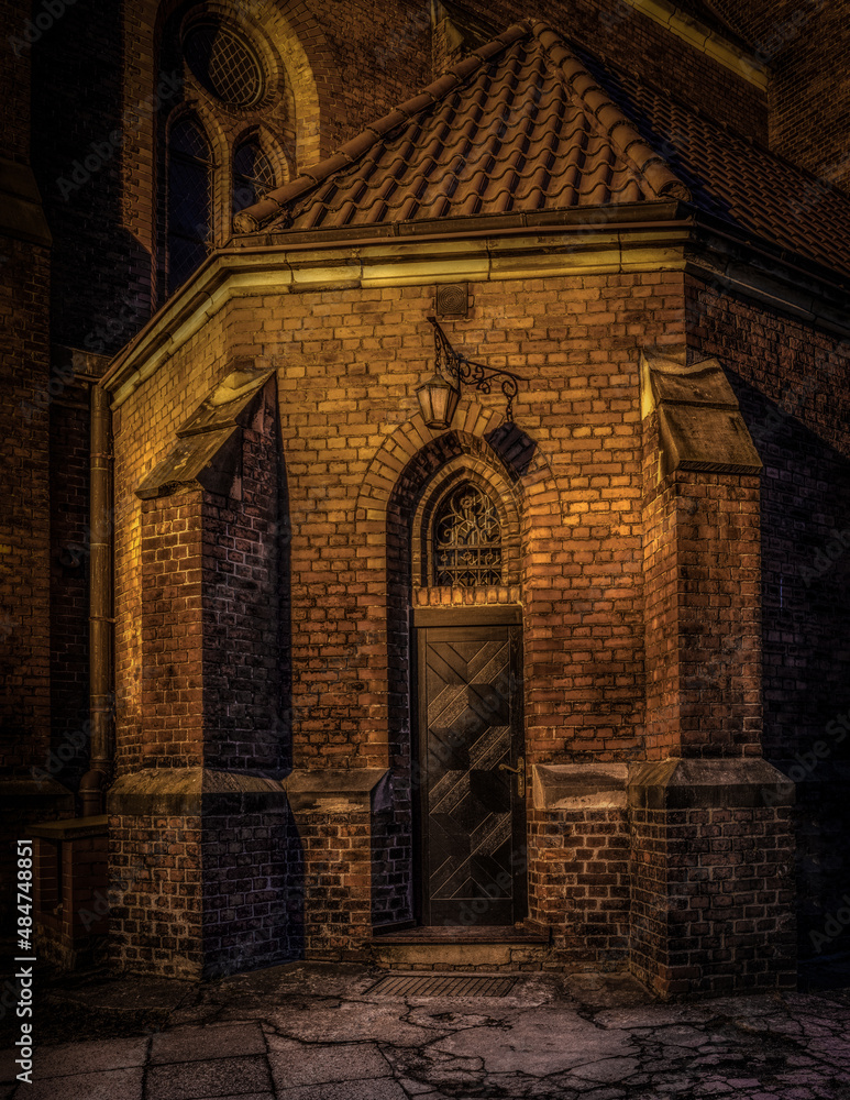 stary gotycki kościół z cegły pięknie oświetlony nocą
