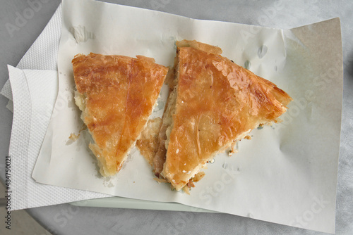 Two slices of fresh juicy burek - traditional pie with cheese, unwrapped, standing on the plate, on a table photo