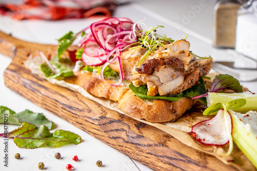 Bruschetta with chicken, radish, microgreens and red onion on a wooden board close-up